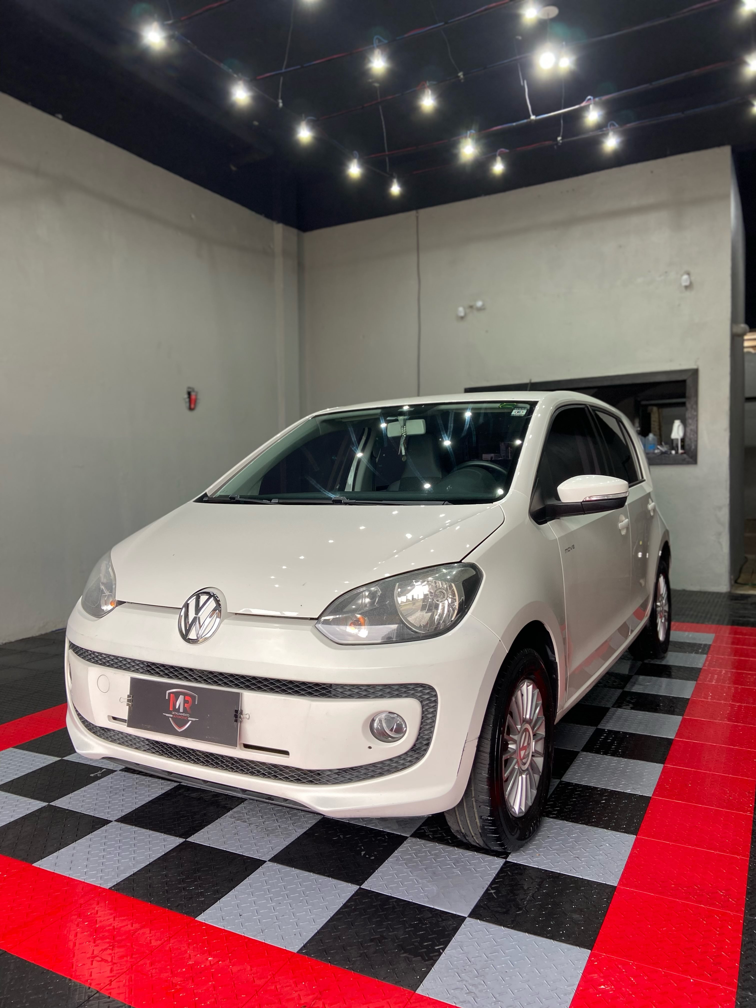 VW Up branco após o detalhamento, no piso preto e vermelho da MR.